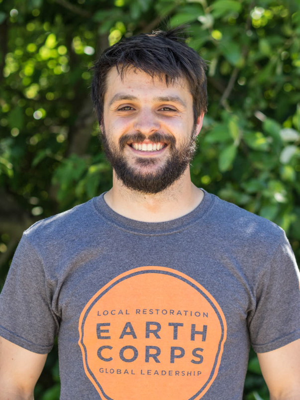 Headshot of EarthCorps alum, Tom Lawler, smiling and wearing an EarthCorps t-shirt. 