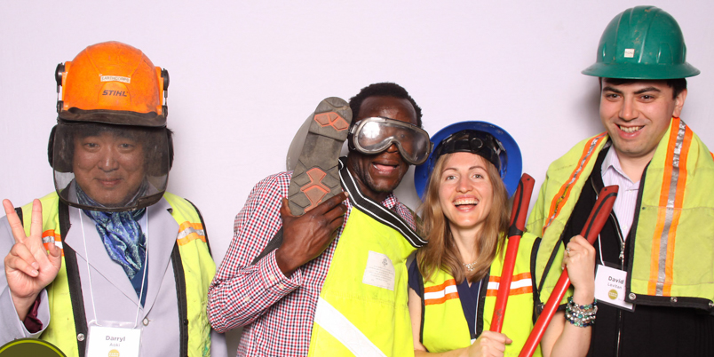 Sarah Gustafson with other Puget Sound Stewards smiling in a photo booth, while holding tools and wearing hardhats.