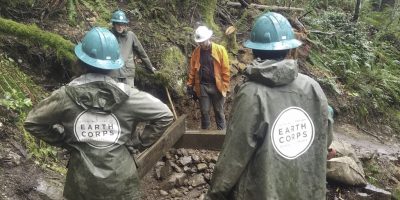 Corps Members on a trail wearing hard hats and rain jackets.
