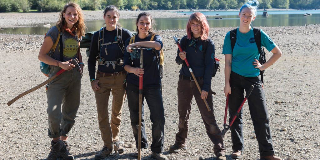 Volunteer Specialist, Amy Hersh, with a small group of Corps Members smiling and holding tools.