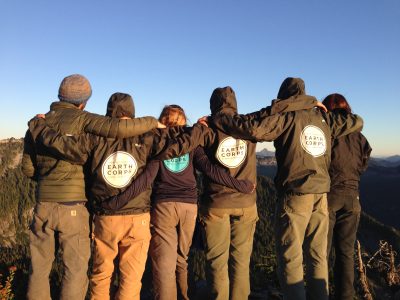 The back of a group of Corps Members embracing each other.