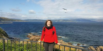 Volunteer Specialist, Amy Hersh, smiling in front of a large body of water.