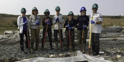 Corps Members and Executive Director, Steve Dubiel, smiling, wearing hard hats and holding tools.