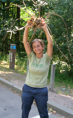 EarthCorps alum, Kayanna Warren, smiling and holding up a root ball. 