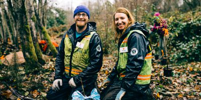 Two smiling Corps Members wearing safety vests and rain jackets.