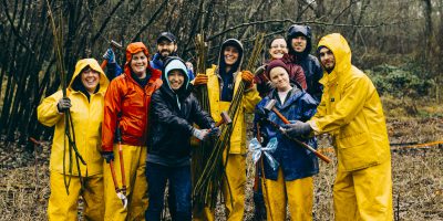 Group of community members, wearing rain gear and holding tools.