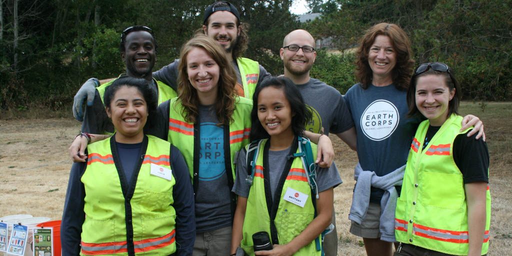 EarthCorps alum, Brittany Le with a group of people smiling and wearing safety vests. 