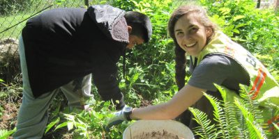 EarthCorps alum, Lindsey Falkenburg smiling while working with a child out in the field.