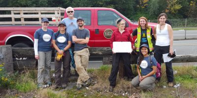 Puget Sound Stewards smiling in front of a red EarthCorps truck.