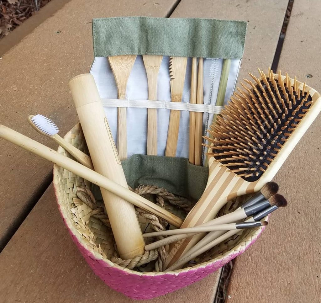 Basket with bamboo products such a bamboo hairbrush, toothbrush, toothbrush holder, utensils, and makeup brushes.