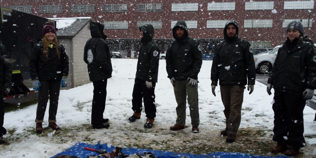 Corps Members standing in the snow doing work skills training. 