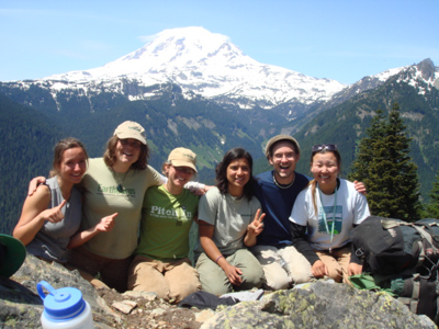 EarthCorps alum Talasi Brooks, with her crew of five Corps Members smiling in front of a mountain landscape.